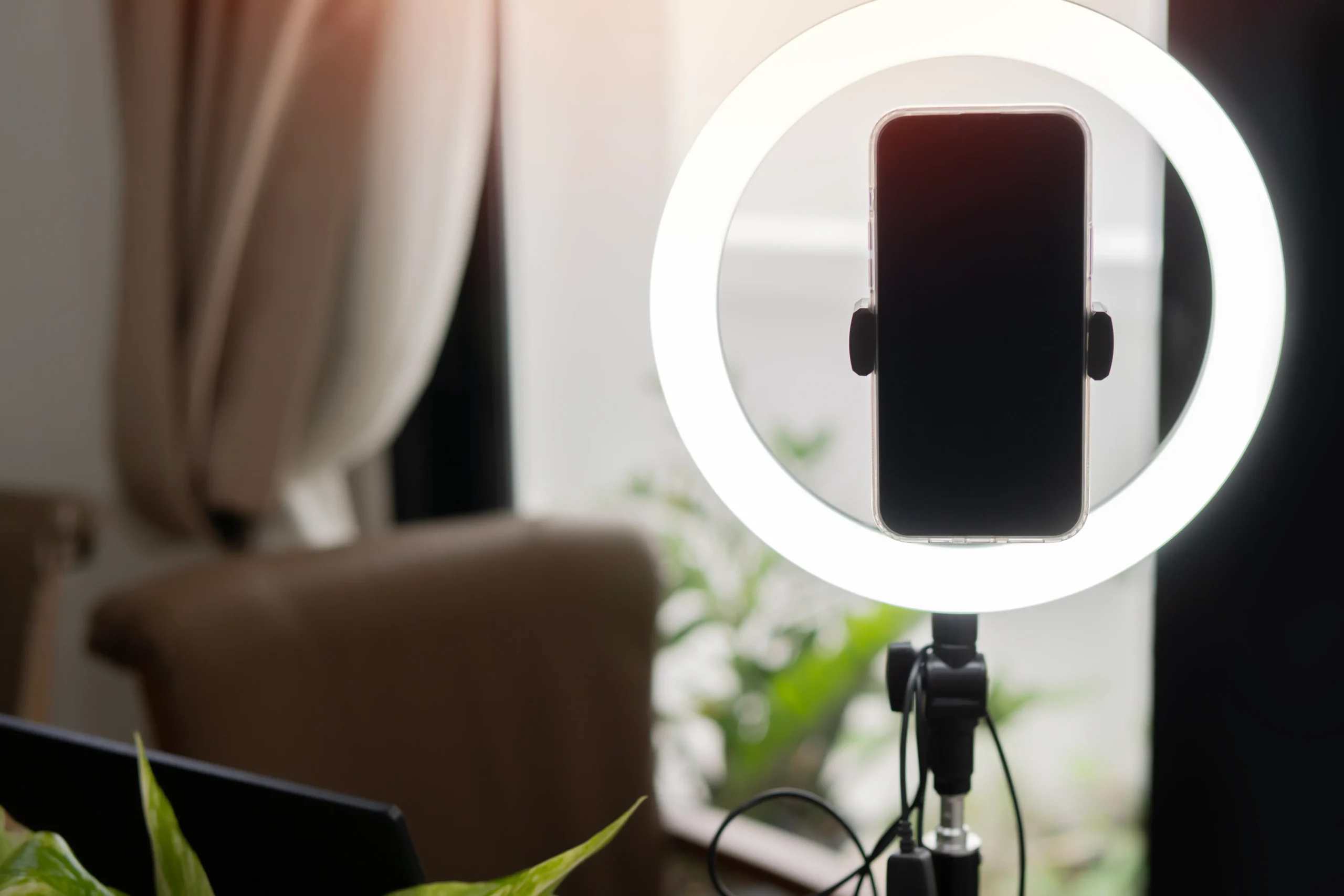 A smartphone mounted on a ring light for recording content in a home space